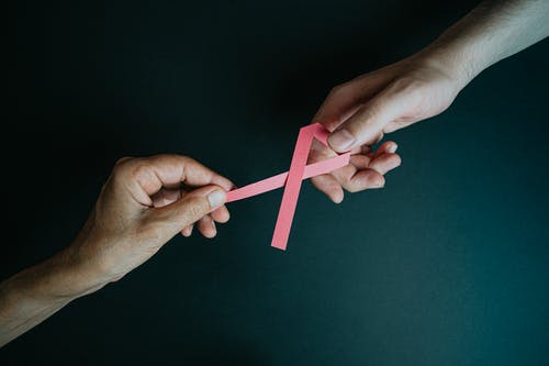 手里捧着乳腺癌粉红色纸丝带 · 免费素材图片