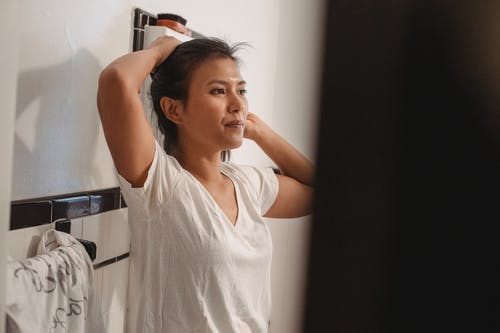 年轻女子在浴室刷头发 · 免费素材图片