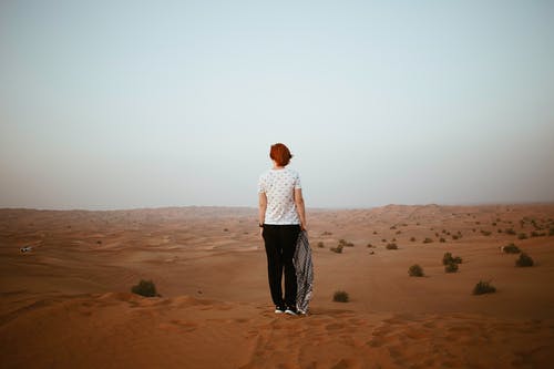 不可识别的女人，在阴云密布的无尽沙漠中 · 免费素材图片