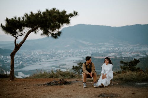 恩爱夫妻坐在城市上空的小山 · 免费素材图片
