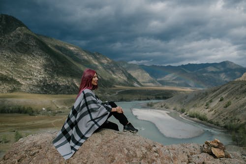 在冰下的山区河流附近休息的女人 · 免费素材图片