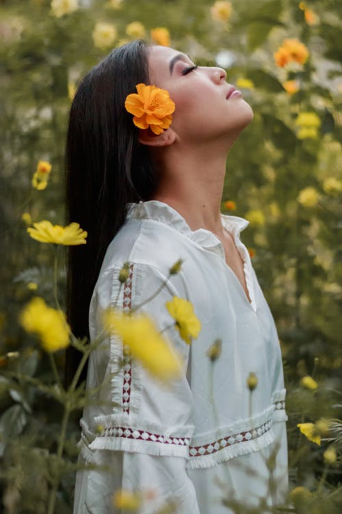 休息在开花的草甸的浪漫年轻亚裔妇女有闭合的眼睛的 · 免费素材图片