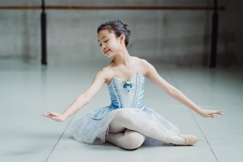 坐在芭蕾舞团的地板上的小民族迷人芭蕾舞女演员 · 免费素材图片