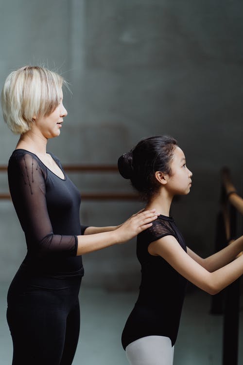 年轻的芭蕾舞老师，帮助初学者的小舞者在工作室 · 免费素材图片