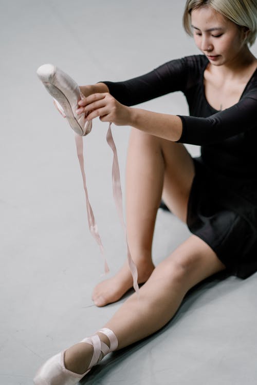 作物芭蕾舞女演员坐在地板上，穿上指针鞋 · 免费素材图片