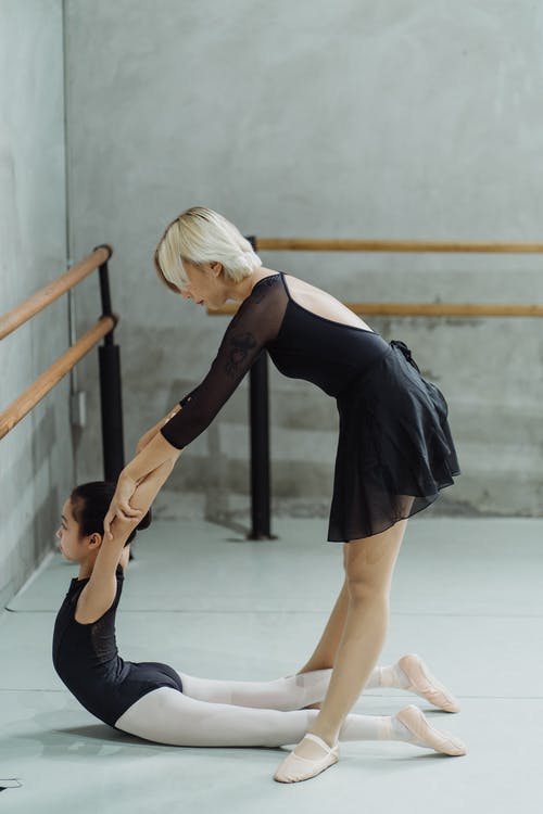 匿名芭蕾舞大师在训练过程中帮助族裔初学者提高背部灵活性 · 免费素材图片