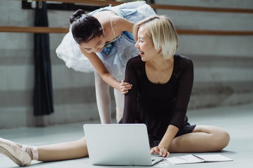 使用膝上型计算机的愉快的亚裔芭蕾舞女演员和女孩实习生在演播室 · 免费素材图片