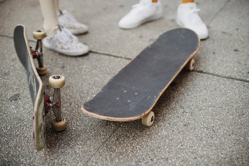 作物不露面溜冰者站在滑板附近的街道上 · 免费素材图片