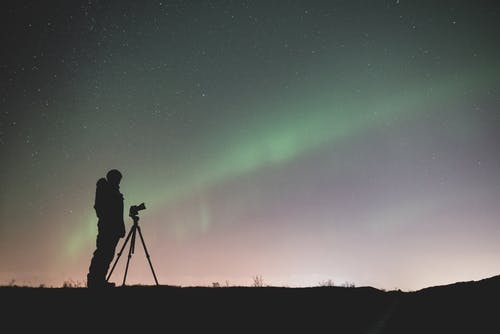 人站在绿色的天空，星星下的岩石上的轮廓 · 免费素材图片