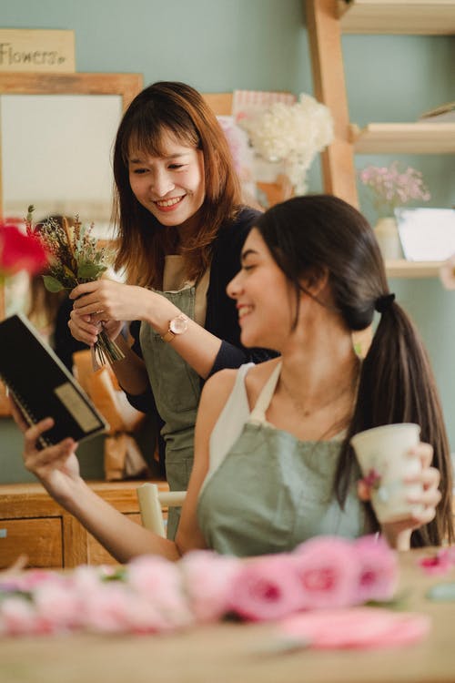 快乐的女人在花店说话 · 免费素材图片