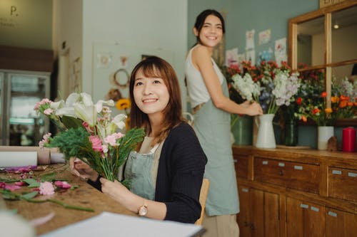 快乐亚洲花店与助手制作花束 · 免费素材图片
