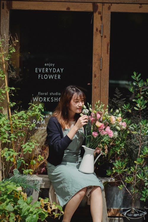 微笑在花束的族裔妇女嗅到的花 · 免费素材图片