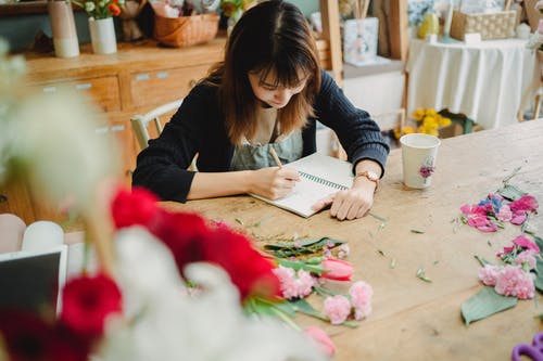 幸福的亚洲女人在商店里写笔记 · 免费素材图片