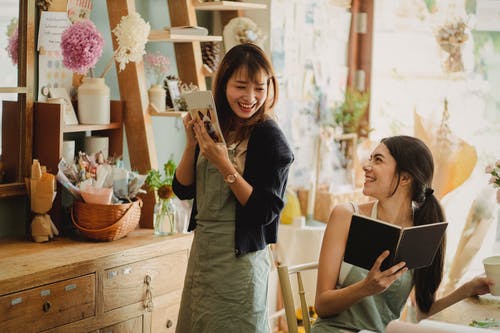 性格开朗的妇女在花店一起工作 · 免费素材图片