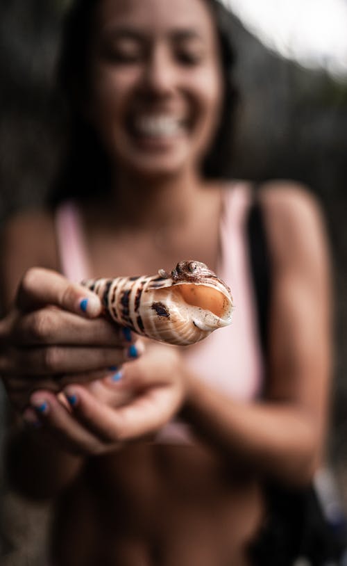 幸福的年轻女人，手里拿着海藻类腹足纲 · 免费素材图片