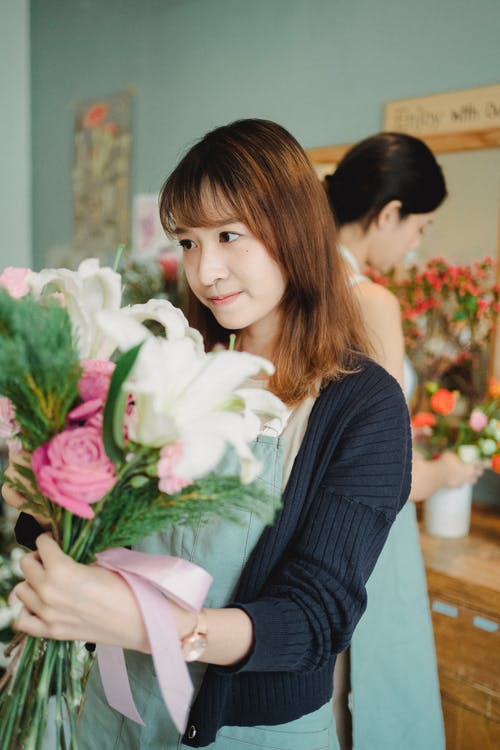 迷人的亚洲花店，站在鲜花店里的花束 · 免费素材图片