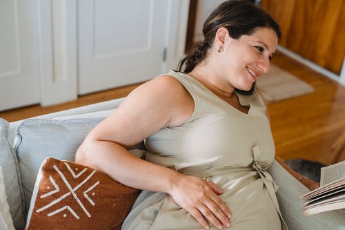 有书的孕妇在沙发 · 免费素材图片