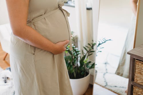 匿名孕妇在家附近镜子站立 · 免费素材图片