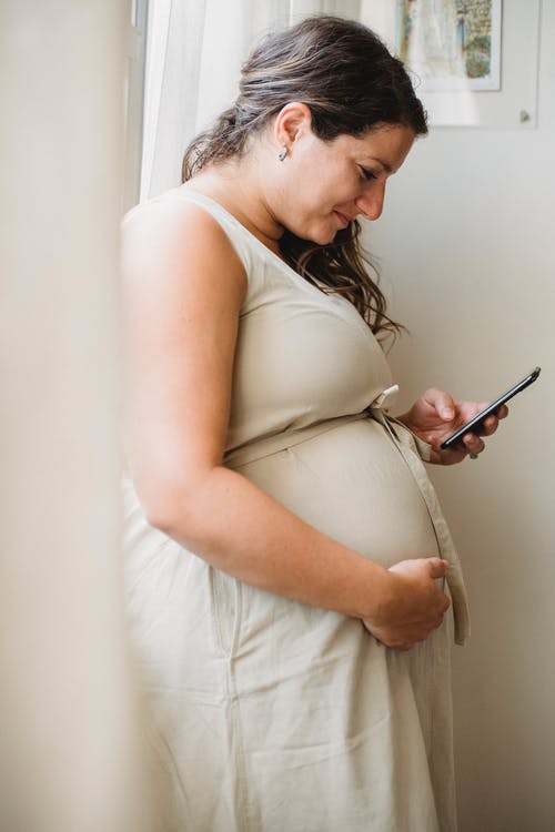 孕妇在站立时检查关于智能手机的通知 · 免费素材图片