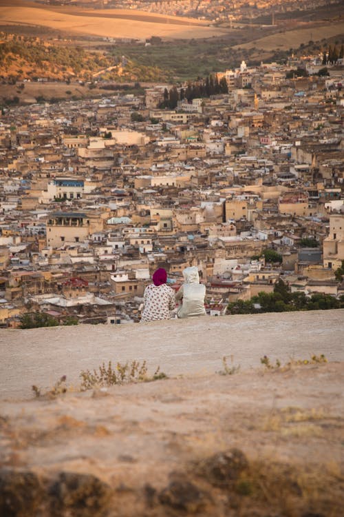 无法识别的女人欣赏山丘上的小镇风景 · 免费素材图片