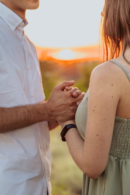 裁剪无法辨认的浪漫情侣手牵着手对落日的天空 · 免费素材图片