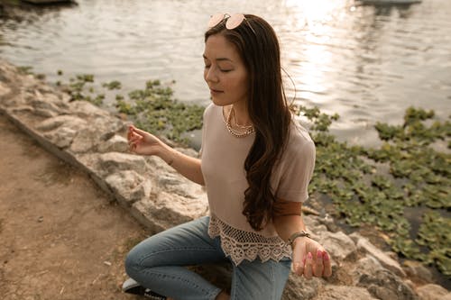 一个女人在湖边打坐 · 免费素材图片