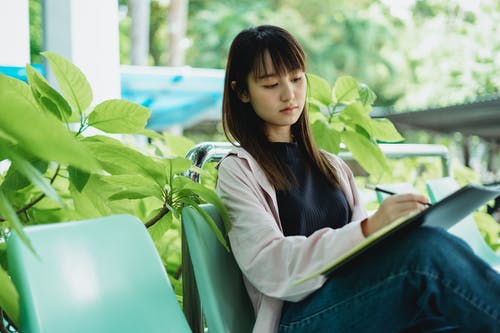 认真的亚洲学生在学习时写在本抄写本 · 免费素材图片