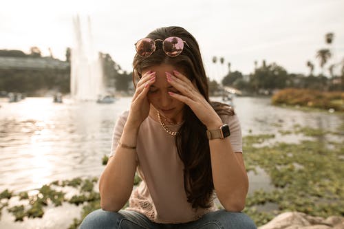 心疼的女人坐在湖边和绝望的摸脸 · 免费素材图片