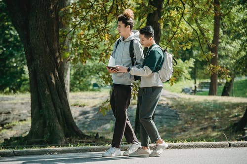 重点突出的年轻多种族男学生在学习之前在公园里读教科书 · 免费素材图片