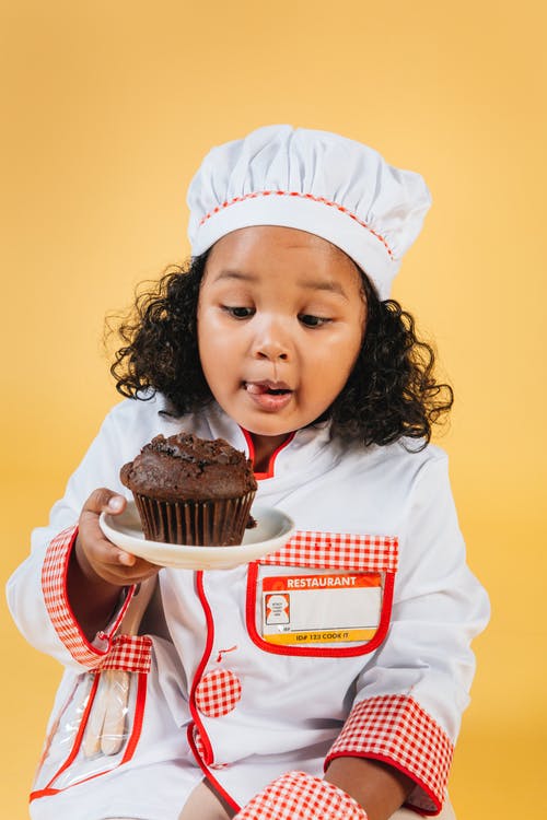 拿着巧克力杯形蛋糕的白色和红色长袖衬衣的女孩 · 免费素材图片