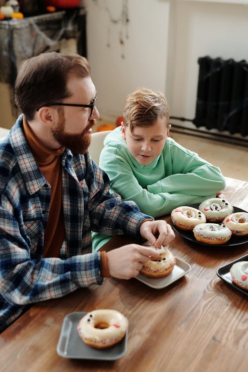 父亲展示他的儿子来装饰甜甜圈 · 免费素材图片