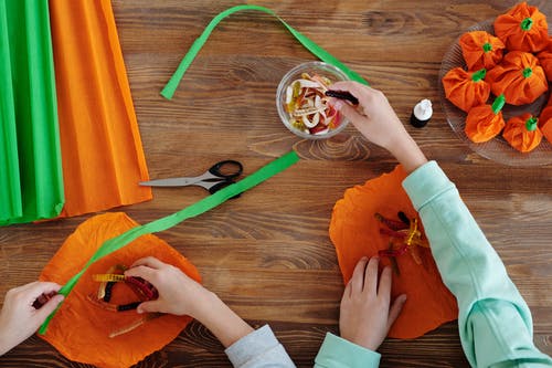 孩子们在橙色纸包装糖果 · 免费素材图片