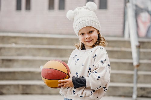 拿着篮球的白色和蓝色的花长袍的女孩 · 免费素材图片