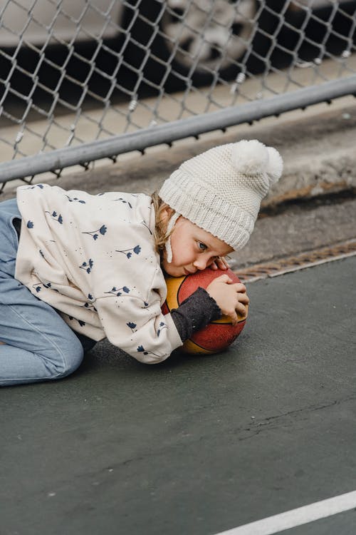 躺在水泥地上的白色和黑色外套的孩子 · 免费素材图片