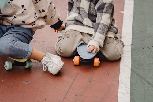 棕色的裤子和白色的鞋子，坐在棕色地板上的人 · 免费素材图片