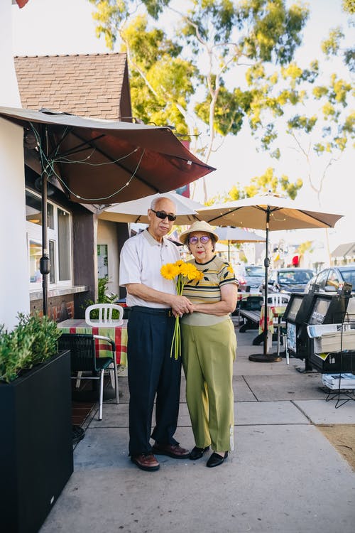 老年夫妇手牵着鲜花花束 · 免费素材图片