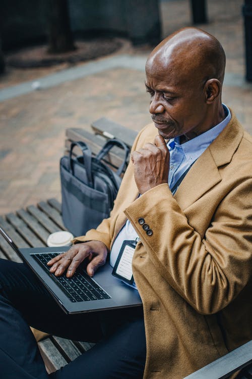 体贴的族裔男性经理，在城市中的笔记本电脑上上网 · 免费素材图片