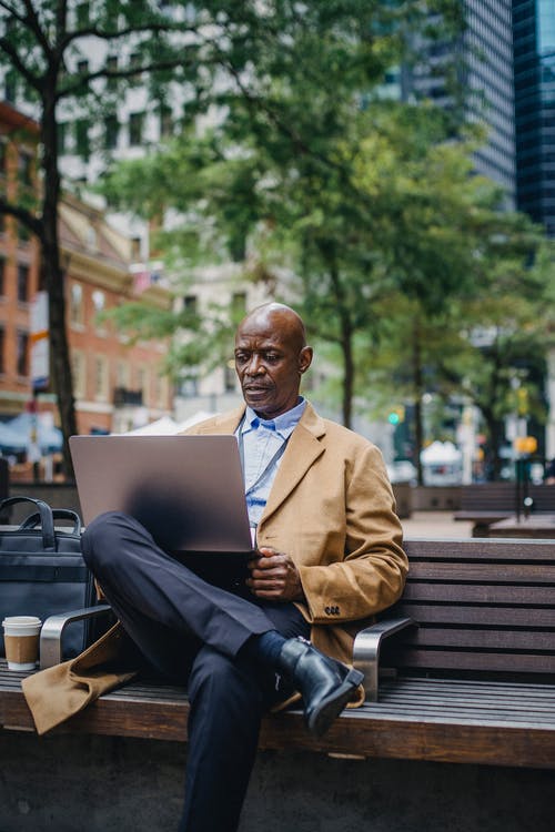 研究在长凳的膝上型计算机的时髦的黑人商人在城市 · 免费素材图片