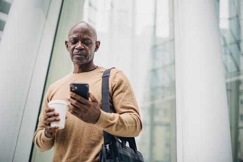 在大街上喝咖啡休息期间在智能手机上聊天的集中成熟的黑人男子 · 免费素材图片