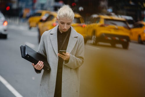 集中在城市道路上观看智能手机的女企业家 · 免费素材图片