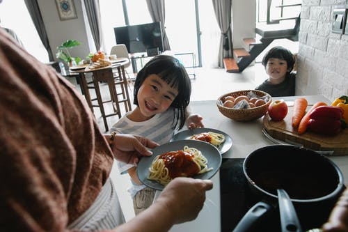 作物女人为可爱的民族孙子们提供美味的意大利面酱 · 免费素材图片