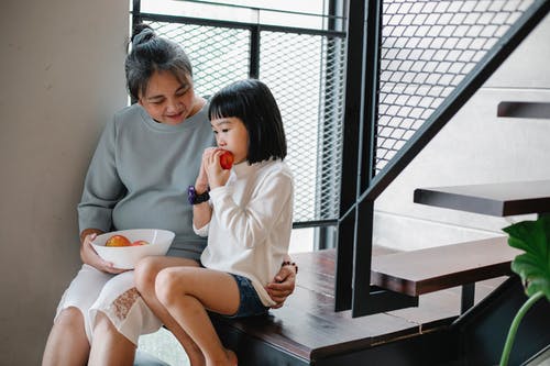 亚洲女人给水果给饥饿的孙女在家里 · 免费素材图片