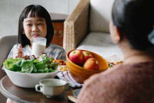 快乐的亚洲小女孩微笑着喝牛奶 · 免费素材图片