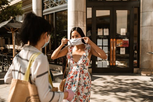 拿着白色智能手机的白色和红色花裙子的女人 · 免费素材图片