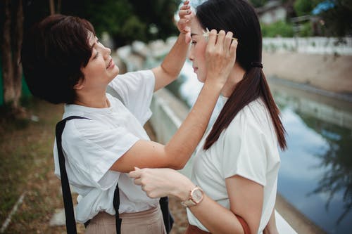 微笑的亚裔妇女感人的同性恋伙伴的前额在堤防上 · 免费素材图片