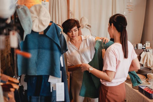 与亚洲女友在店里挑选衣服的无法识别的购物者 · 免费素材图片