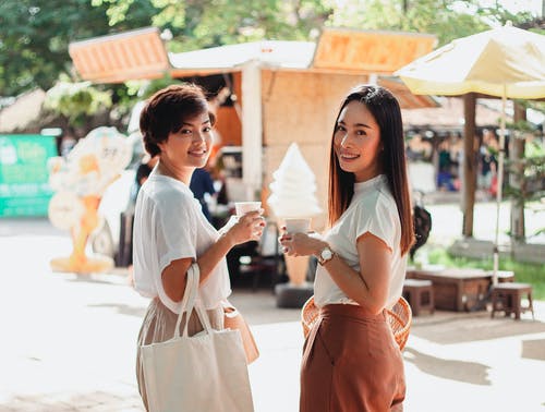 站立与咖啡的美满的亚裔妇女在市场上 · 免费素材图片