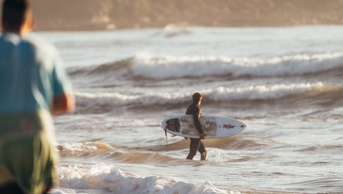 冲浪者在强大的波浪海洋中行走 · 免费素材图片