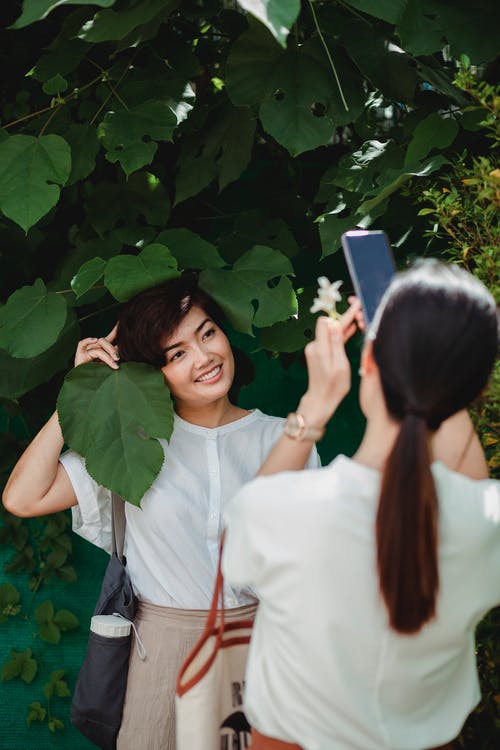 不可识别的女人拍照的亚洲朋友在智能手机上的 · 免费素材图片
