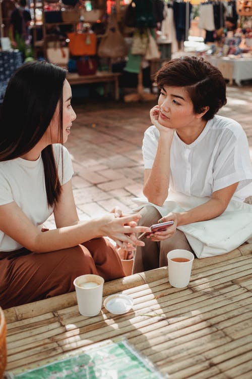 积极的亚洲妇女聊天，在户外咖啡馆喝咖啡 · 免费素材图片